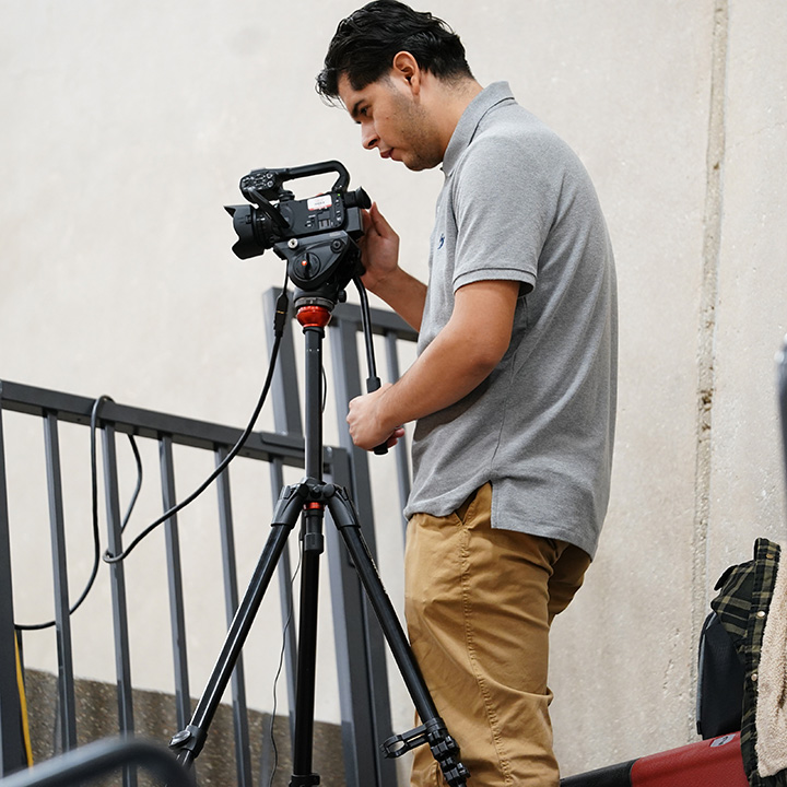 Student Sports Media Worker with Video Camera on Tripod